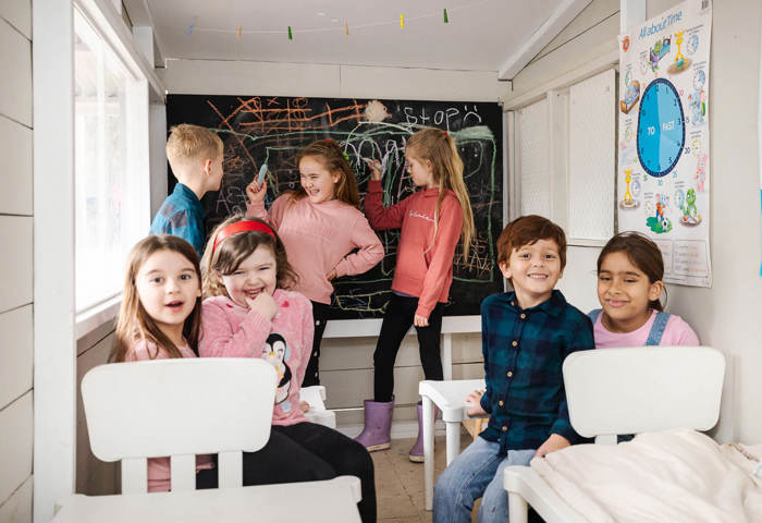 Kids In Classroom At Cubby Cafe Drawing On Chalkboard