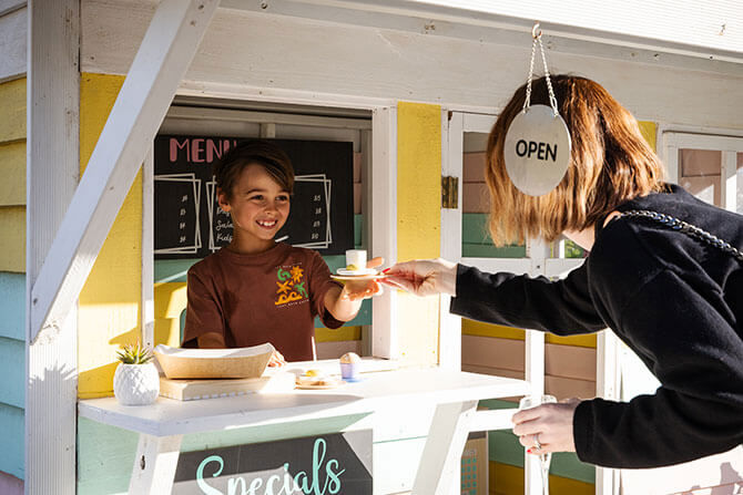 Boy Handing His Mum A Cup Of Coffee At Cubby Cafe